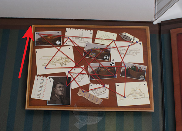Photo of described steps, with arrow pointing to top left of corkboard